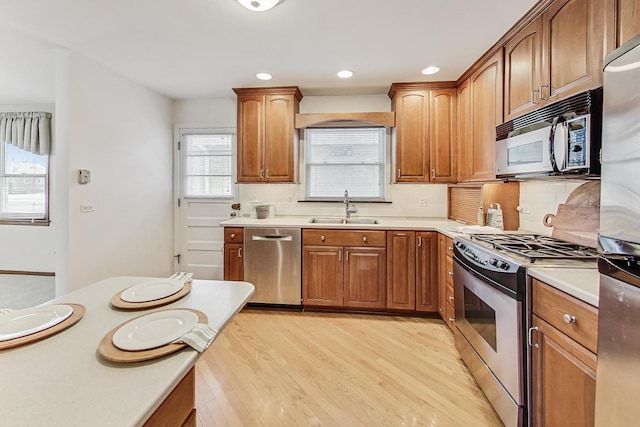 kitchen featuring sink, light hardwood / wood-style floors, tasteful backsplash, and appliances with stainless steel finishes