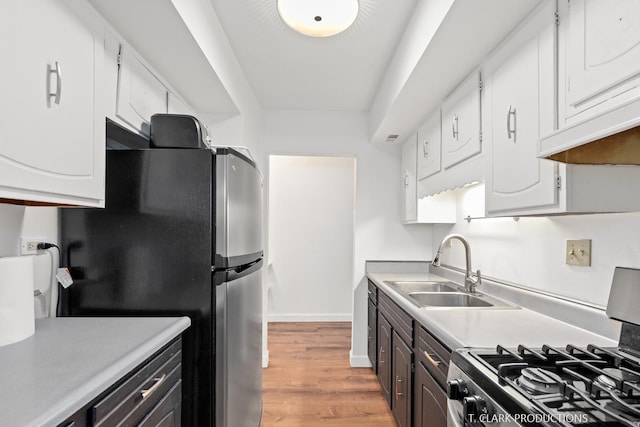 kitchen featuring stainless steel appliances, white cabinets, sink, and light wood-type flooring