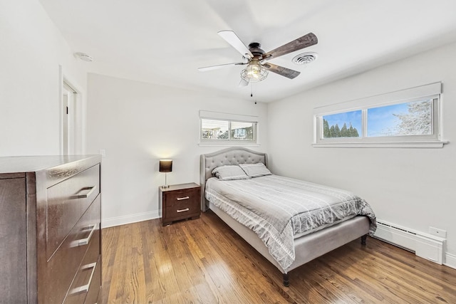 bedroom with hardwood / wood-style flooring, a baseboard radiator, and ceiling fan