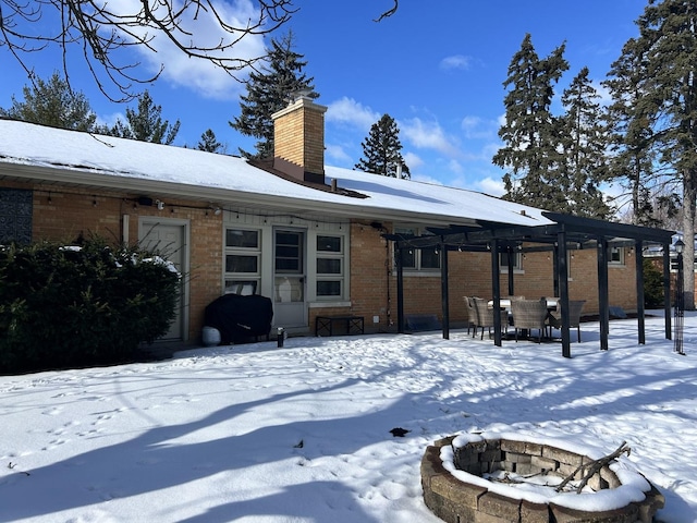 snow covered property with an outdoor fire pit