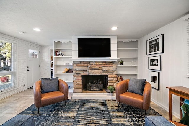 sitting room with a textured ceiling, built in features, and a stone fireplace