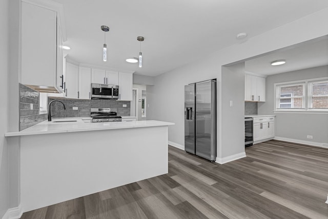 kitchen featuring stainless steel appliances, white cabinets, sink, and kitchen peninsula