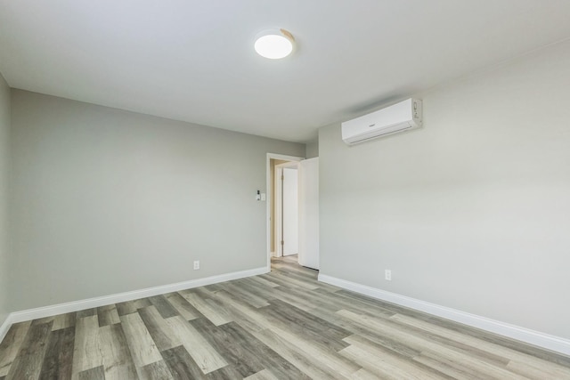 empty room featuring an AC wall unit and light wood-type flooring