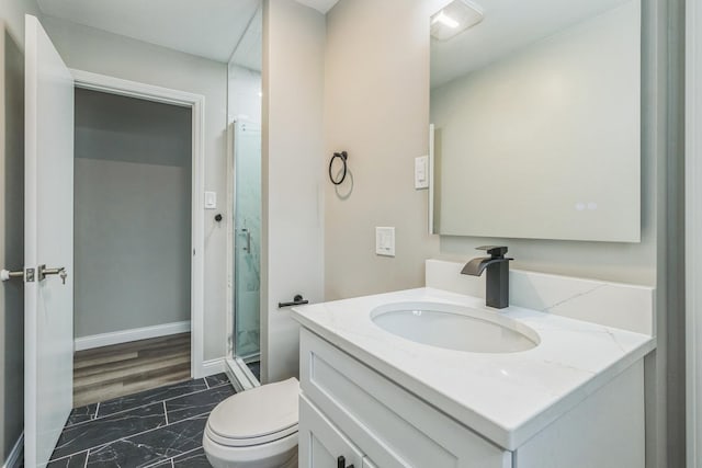 bathroom featuring a shower with shower door, vanity, and toilet