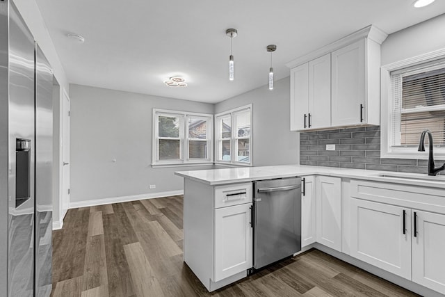 kitchen featuring stainless steel dishwasher, decorative light fixtures, decorative backsplash, white cabinets, and sink