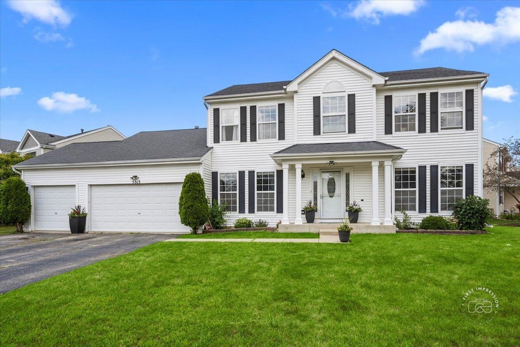 colonial house featuring a front yard and a garage