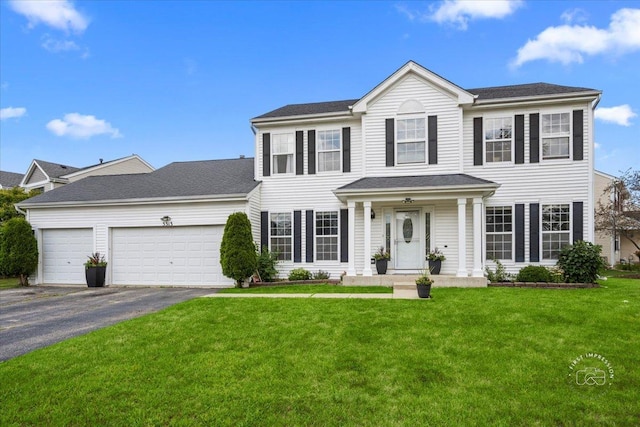 colonial house featuring a front yard and a garage