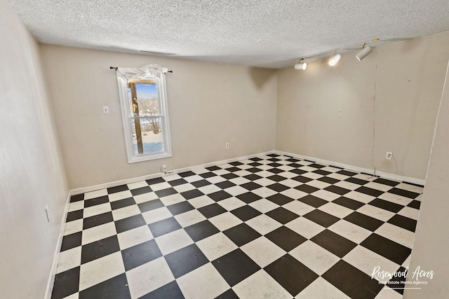 empty room featuring a textured ceiling and rail lighting