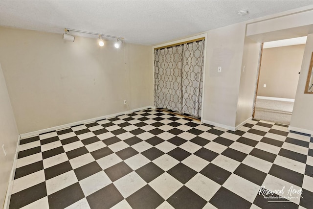 basement with a textured ceiling and rail lighting