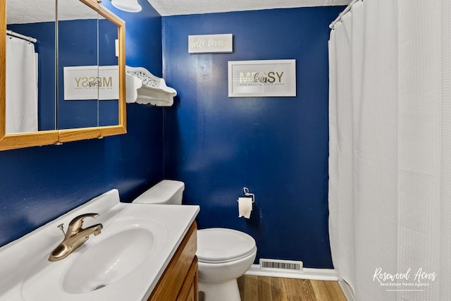 bathroom featuring toilet, vanity, a textured ceiling, and hardwood / wood-style floors