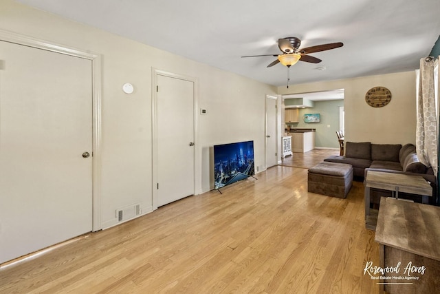 living room with ceiling fan and light hardwood / wood-style flooring