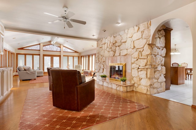 living room with hardwood / wood-style flooring, ceiling fan, vaulted ceiling with beams, and a fireplace