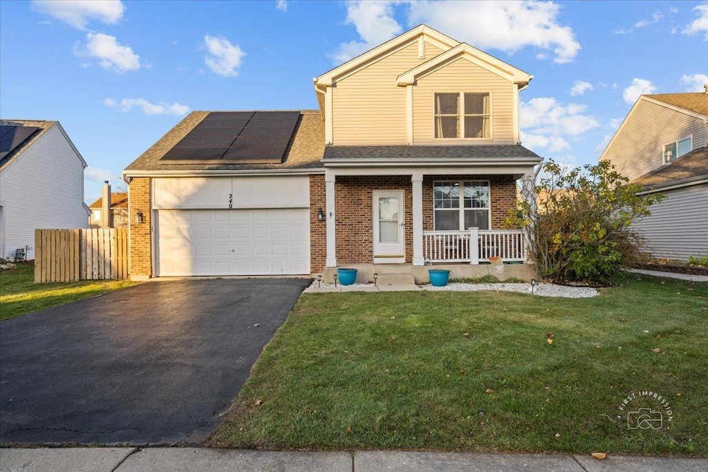 view of front of home with solar panels, covered porch, a front lawn, and a garage