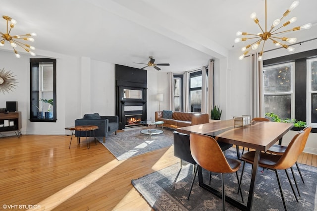 dining room with ceiling fan with notable chandelier and hardwood / wood-style flooring