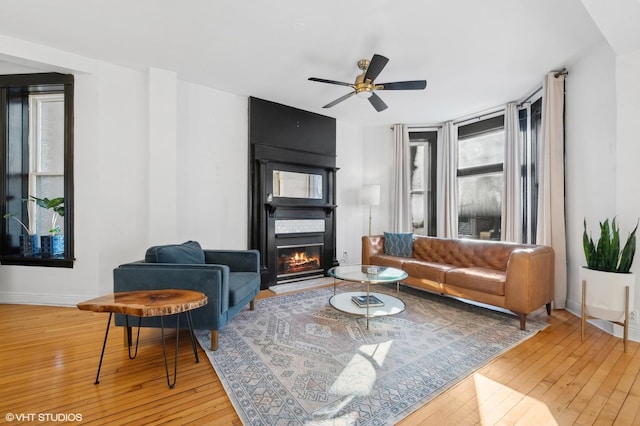 living room with ceiling fan, a fireplace, and wood-type flooring