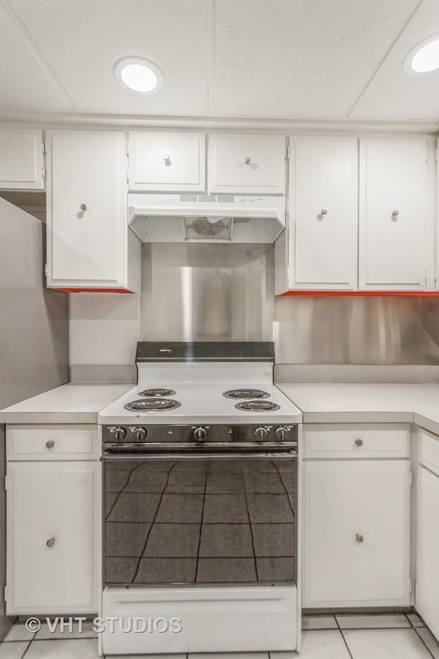 kitchen featuring light tile patterned floors, white cabinets, and range with electric cooktop