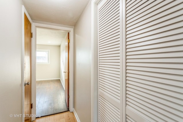 corridor featuring a textured ceiling and light hardwood / wood-style flooring