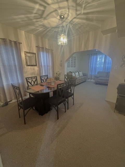 unfurnished dining area featuring a chandelier and carpet