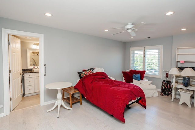 bedroom with light wood-type flooring, ceiling fan, and connected bathroom