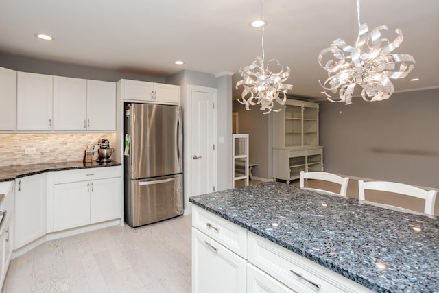 kitchen featuring decorative light fixtures, stainless steel refrigerator, an inviting chandelier, and white cabinetry