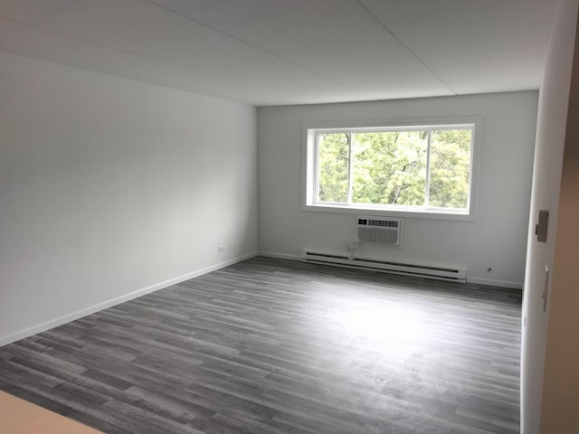 spare room featuring baseboard heating, dark hardwood / wood-style floors, and an AC wall unit