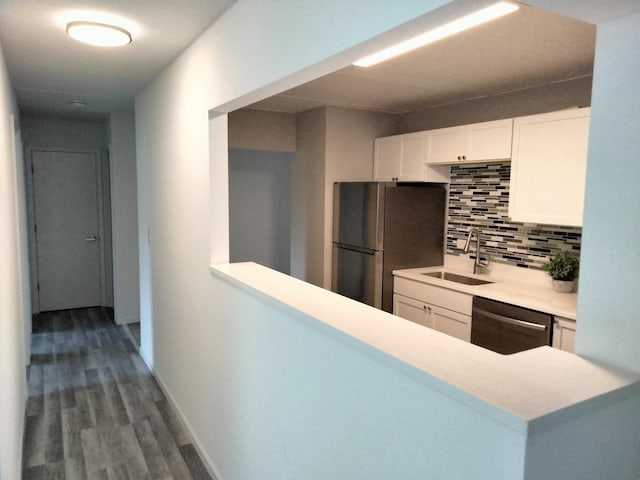 kitchen with tasteful backsplash, wood-type flooring, sink, white cabinetry, and appliances with stainless steel finishes