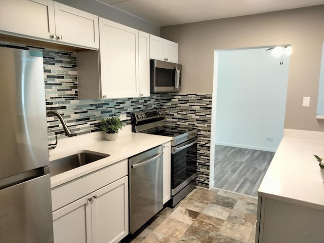 kitchen featuring backsplash, sink, stainless steel appliances, and white cabinetry