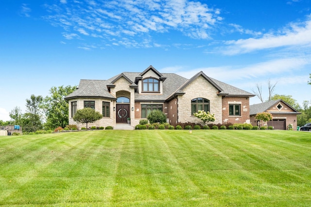 french country home featuring a front lawn and a garage