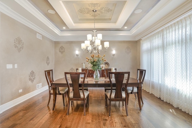 dining room featuring crown molding, wood-type flooring, a tray ceiling, and a notable chandelier