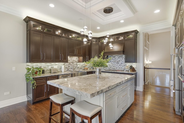 kitchen with light stone countertops, crown molding, hanging light fixtures, and a center island