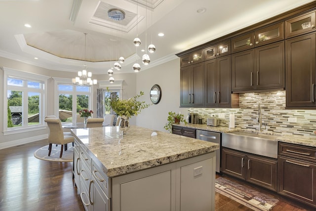 kitchen featuring a kitchen island, sink, hanging light fixtures, a tray ceiling, and crown molding