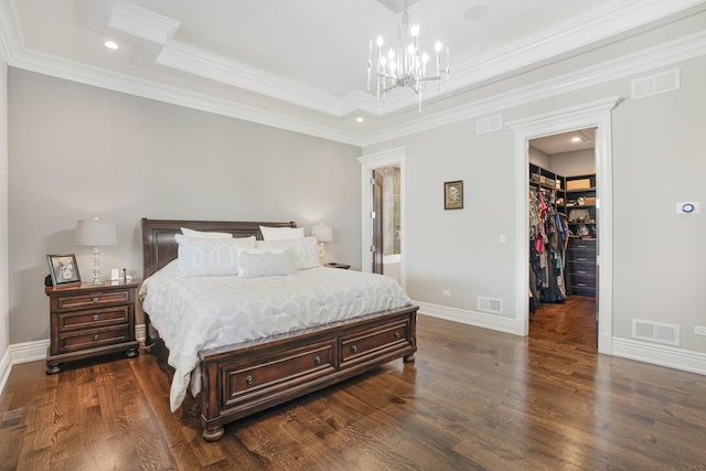 bedroom with a walk in closet, a tray ceiling, dark hardwood / wood-style floors, ensuite bathroom, and crown molding