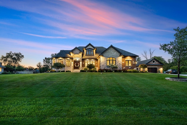 french country style house with a garage and a lawn