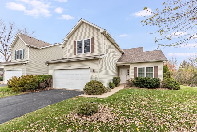 traditional-style house featuring aphalt driveway, an attached garage, and a front lawn