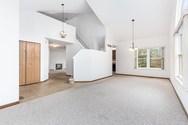 unfurnished living room featuring high vaulted ceiling, carpet, and a chandelier