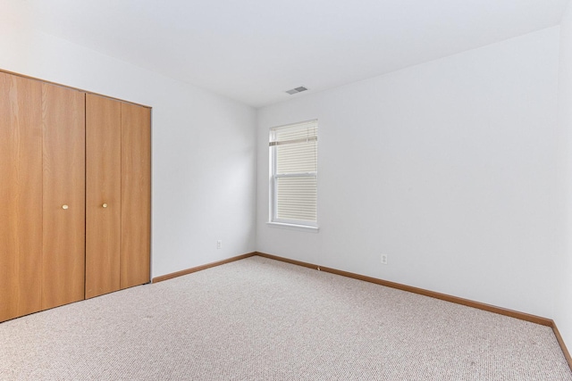 unfurnished bedroom featuring visible vents, carpet flooring, baseboards, and a closet