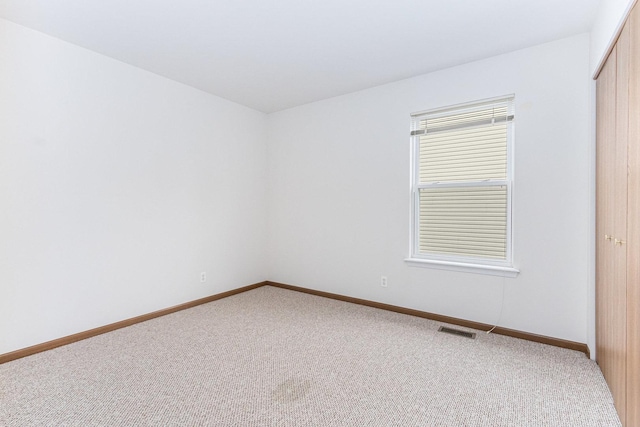 carpeted empty room with visible vents and baseboards