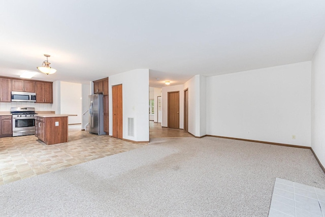 kitchen featuring light carpet, open floor plan, appliances with stainless steel finishes, and light countertops