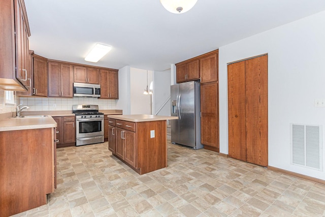 kitchen with visible vents, a sink, stainless steel appliances, light countertops, and backsplash