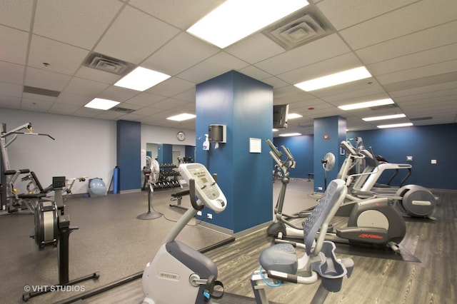 exercise room with wood-type flooring and a paneled ceiling