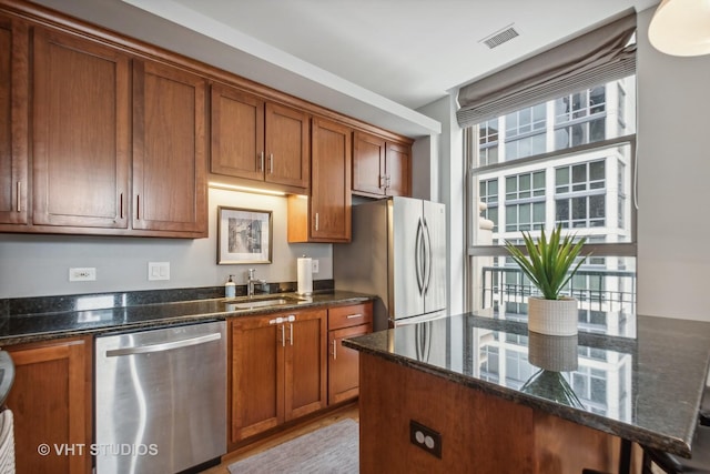 kitchen with appliances with stainless steel finishes, sink, and dark stone countertops