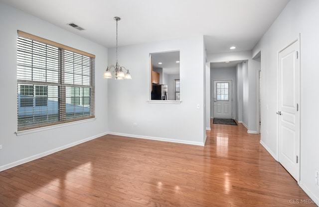 unfurnished dining area featuring wood-type flooring and a notable chandelier