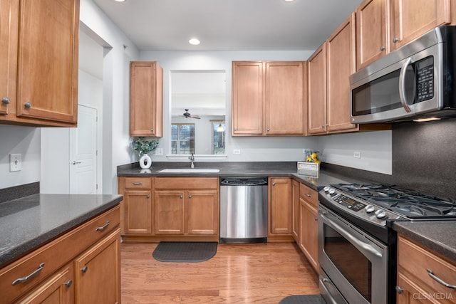 kitchen with ceiling fan, sink, appliances with stainless steel finishes, and light hardwood / wood-style flooring