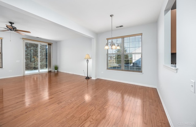 unfurnished room with hardwood / wood-style flooring and ceiling fan with notable chandelier