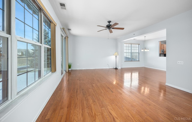 empty room with ceiling fan with notable chandelier and hardwood / wood-style flooring