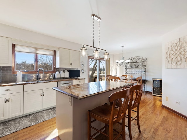 kitchen with a wealth of natural light, white cabinetry, sink, and a center island