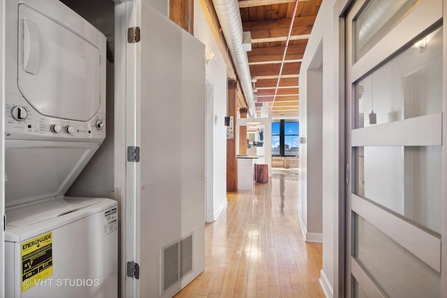 laundry room with light hardwood / wood-style flooring and stacked washer / dryer