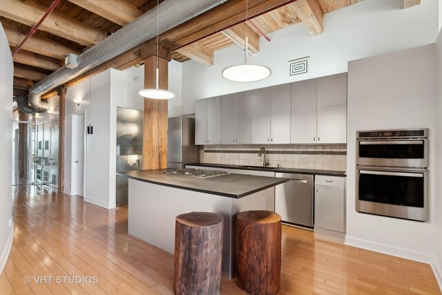 kitchen featuring tasteful backsplash, hanging light fixtures, beam ceiling, white cabinets, and sink