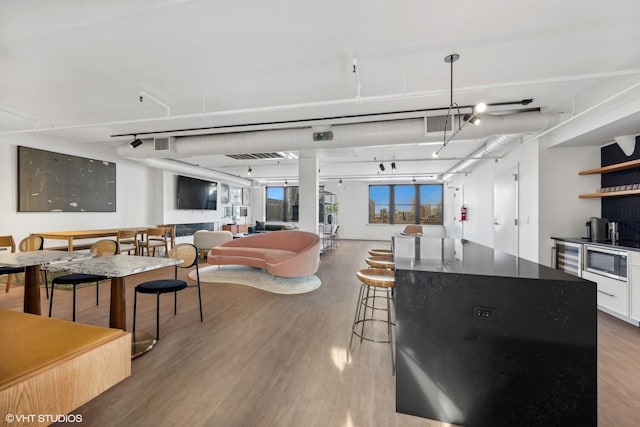 kitchen with stainless steel microwave, rail lighting, white cabinets, a center island, and light wood-type flooring