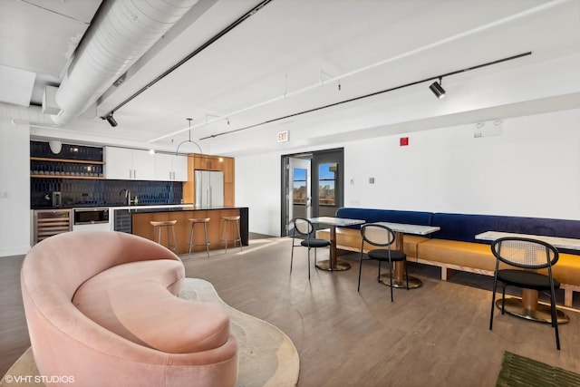 interior space with tasteful backsplash, white cabinets, beverage cooler, hanging light fixtures, and fridge